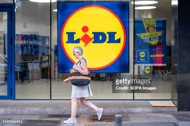 Pedestrian walks past the German international discount retail chain supermarket, Lidl, seen in Spain.