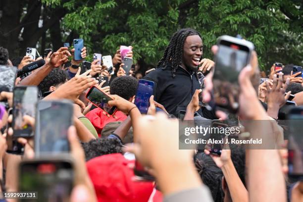 People gather around and cheer for Kai Cenat as members of the NYPD respond to thousands of people gathered for a "giveaway" event announced by...