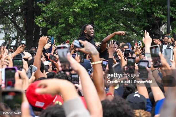 People gather around and cheer for Kai Cenat as members of the NYPD respond to thousands of people gathered for a "giveaway" event announced by...