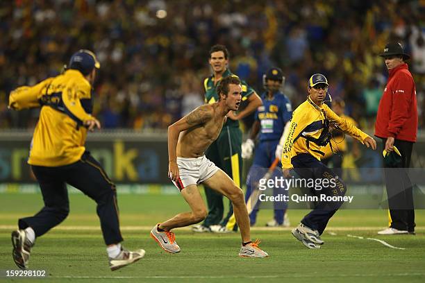 Pitch invader tries to outrun security during game one of the Commonwealth Bank One Day International series between Australia and Sri Lanka at...
