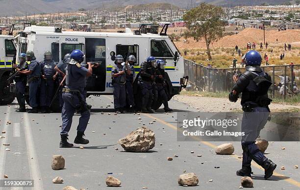 Police hold off striking farm workers as they make barricades to block off the N2 on January 10, 2013 in Grabouw, South Africa. Seasonal farm workers...