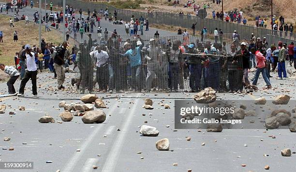 Striking Farm workers stand behind fencing as Police fight to hold them off from making barricades to block off the N2 on January 10, 2013 in...