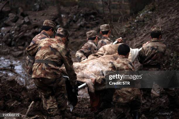 Chinese rescue workers carry a dead body they found while searching for buried residents in a disaster-hit area in Gaopo village, southwest China's...