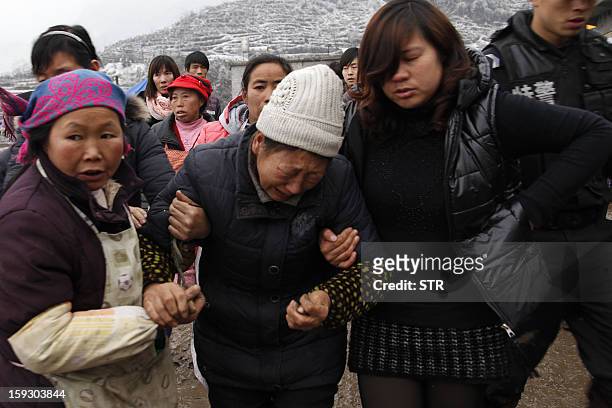 Chinese residents help carry a crying woman in a disaster-hit area in Gaopo village, southwest China's Yunnan province on January 11, 2013. A...