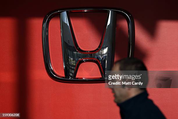Honda worker passes a Honda logo at the Honda car assembly plant following the announcement that the firm is to axe 800 jobs on January 11, 2013 in...