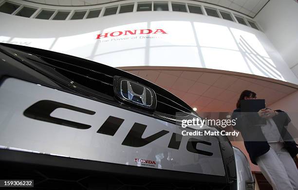 Honda worker passes a brand new Honda Civic displayed in the reception of a office building at the Honda car assembly plant following the...