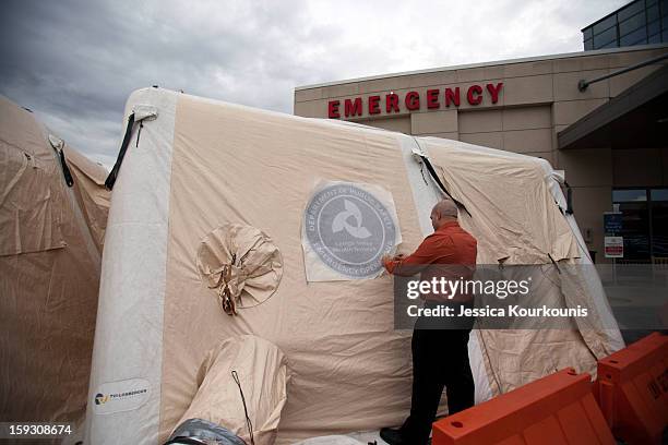 Luis Puentes, Director of Emergency Preparedness at Lehigh Valley Health Network's main hospital campus, applies a decal to a mobile tent set up to...