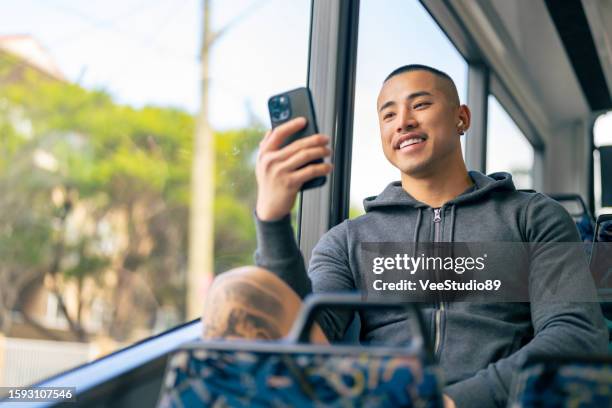 asian man using mobile phone on the bus. - person looking at phone while smiling australia stock pictures, royalty-free photos & images