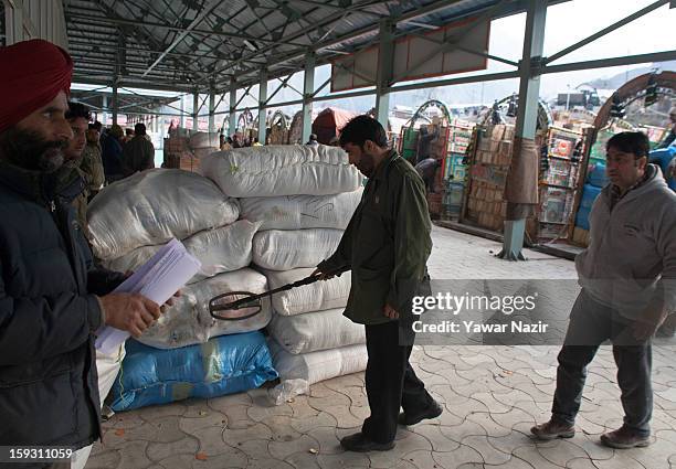 An Indian policeman checks unloaded goods from Pakistani vehicles with his metal detector at the trade facilitation centre in the border area near...