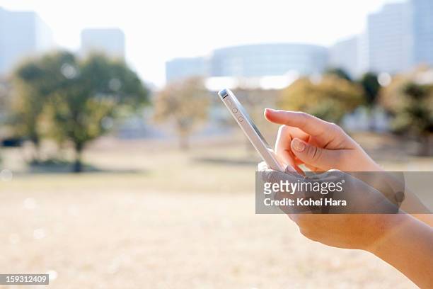 hands of a woman using a smart phone in the park - kanagawa prefecture fotografías e imágenes de stock