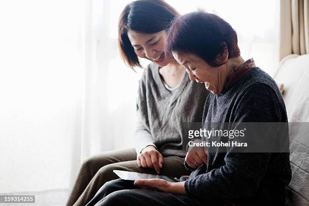 family watching a digital tablet together - japanese mom stock pictures, royalty-free photos & images