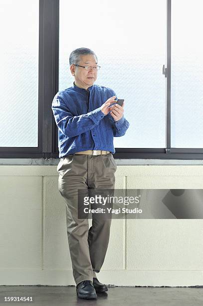 senior man using smartphone - pantalon beige photos et images de collection