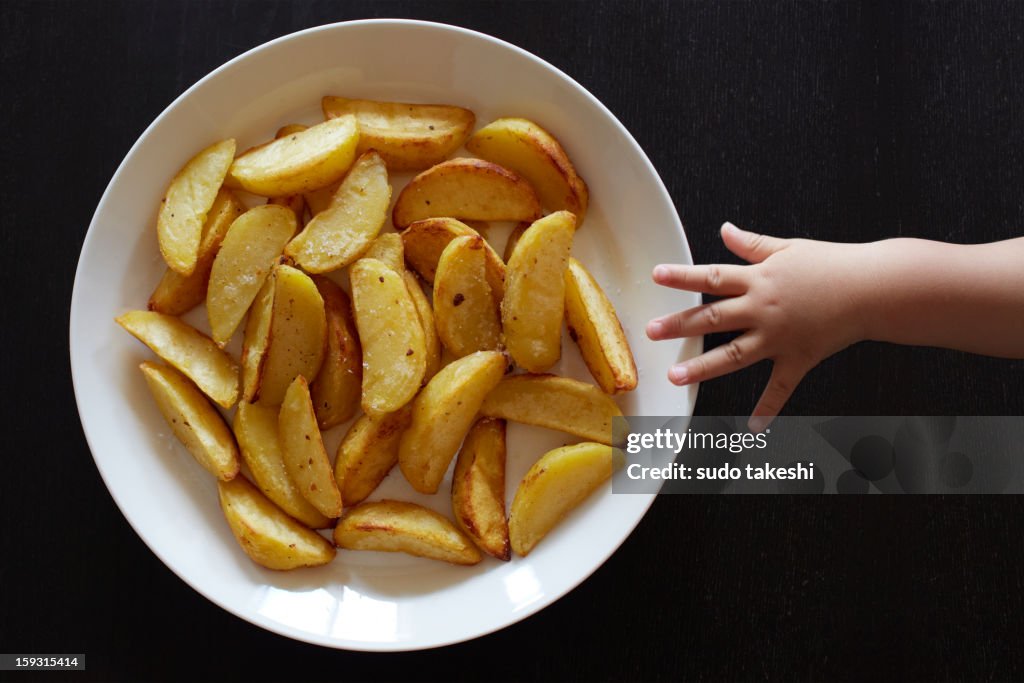 Hand of a child trying to grab the fries.