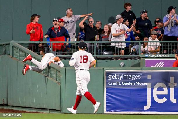 Jarren Duran of the Boston Red Sox goes over the wall as teammate Adam Duvall of the Boston Red Sox runs to assist in the ninth inning against the...