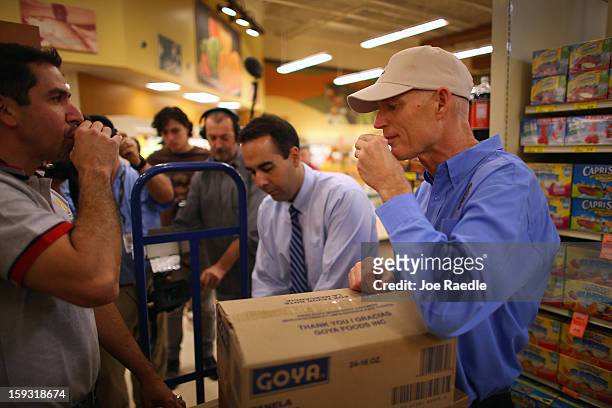 Florida Governor Rick Scott drinks Cuban coffee with Jorge Rodriguez as they stock the shelves with Goya products at the Sedano’s Supermarket on...