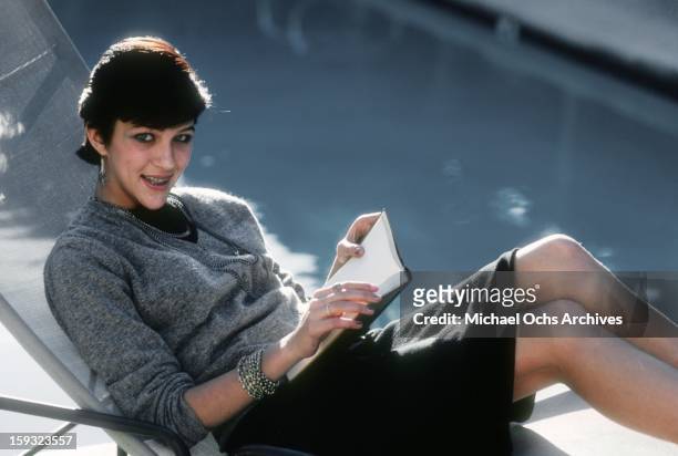 Actress and TV personality Allegra Curtis reads by the pool at home in January 1982 in Los Angeles, California.