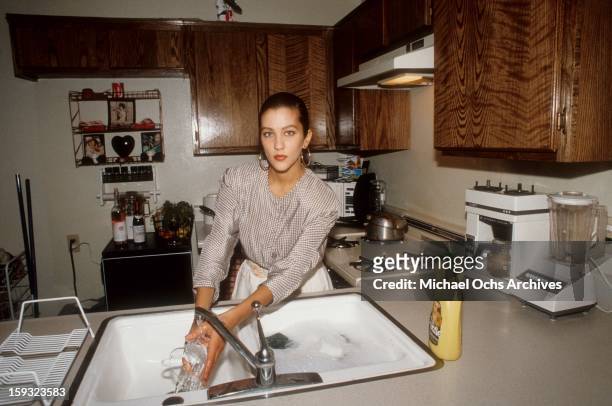 Actress and TV personality Allegra Curtis washes the dishes at home in 1988 in Los Angeles, California.