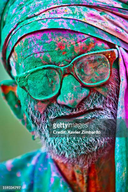 Portrait of a man covered with coloured powdered dye and coloured water that people throw on each other during Holi, the merriest of all the Hindu...