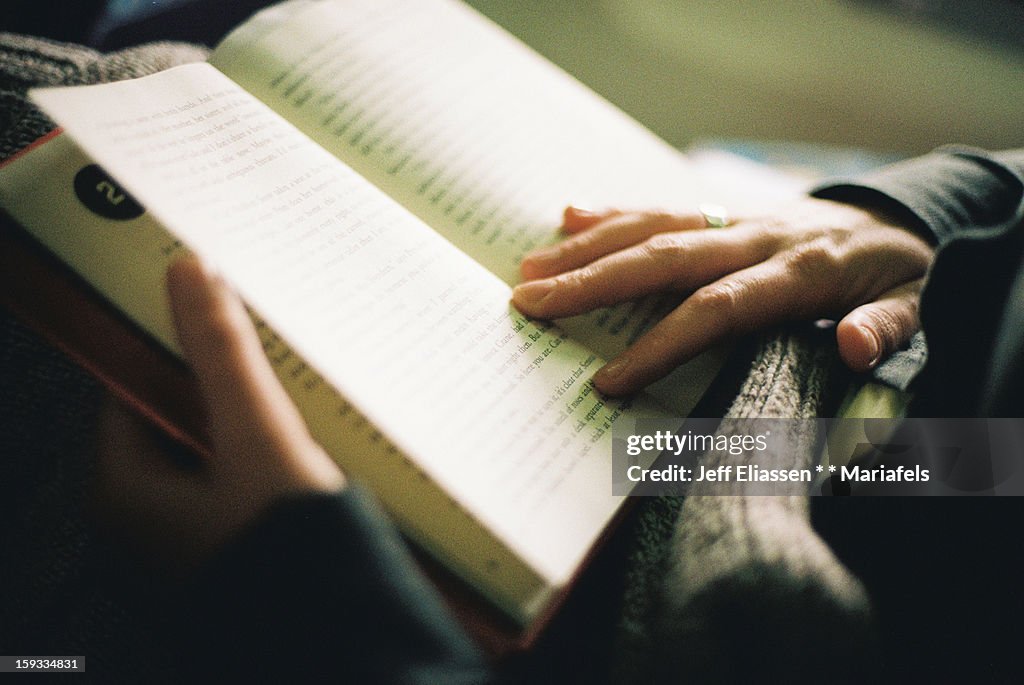 Woman reading a book, indoor light, hands close-up