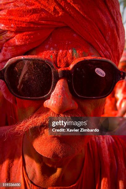 Portrait of an old man covered with coloured powdered dye and coloured water that people throw on each other during Holi, the merriest of all the...