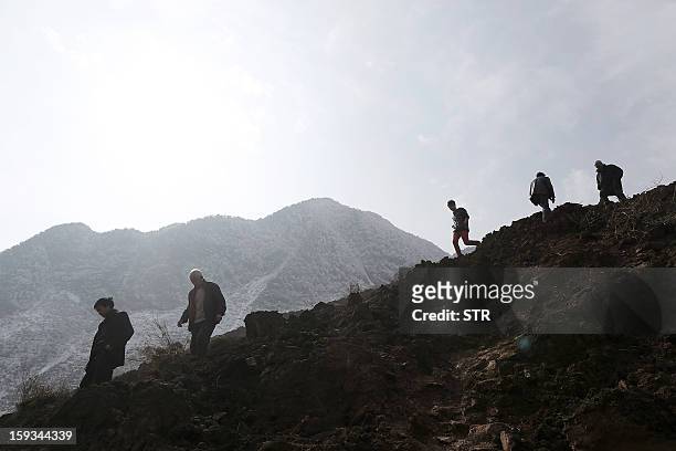 Local residents look at the buried area from the collapsed hill to see how the landslide happened in Gaopo village, southwest China's Yunnan province...