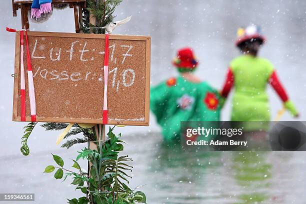 Ice swimming enthusiasts enter the cold waters of Orankesee lake next to a sign displaying air and water temperatures during the 'Winter Swimming in...