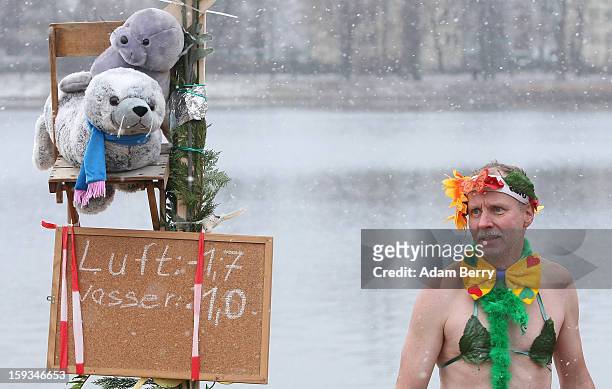 An ice swimming enthusiast prepares to enter the cold waters of Orankesee lake next to a sign displaying air and water temperatures during the...
