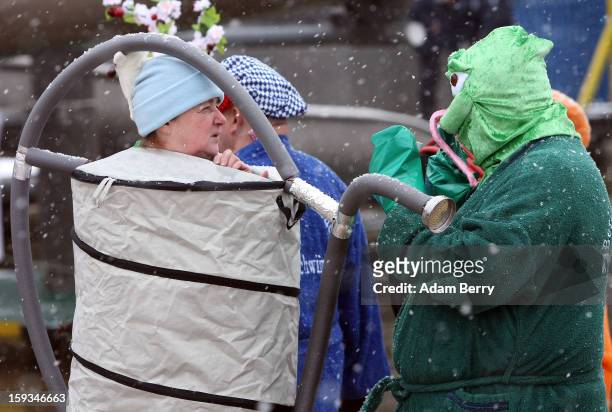 Ice swimming enthusiasts dressed as a frog and a watering can prepare to enter the cold waters of Orankesee lake during the 'Winter Swimming in...