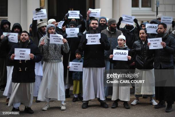 Muslim men and children hold up signs reading "Jihad for Mali", "United Nations go to hell" and calling French President Francois Hollande a...