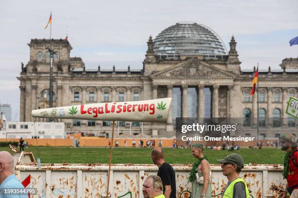 Cannabis supporters march with a giant mock joint reading "Legalization" past the Reichstag building in the annual Hemp Parade on August 12, 2023 in...