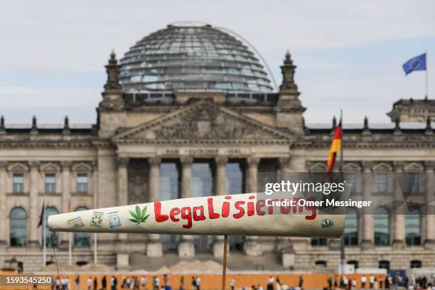 Cannabis supporters march with a giant mock joint reading "Legalization" past the Reichstag building in the annual Hemp Parade on August 12, 2023 in...