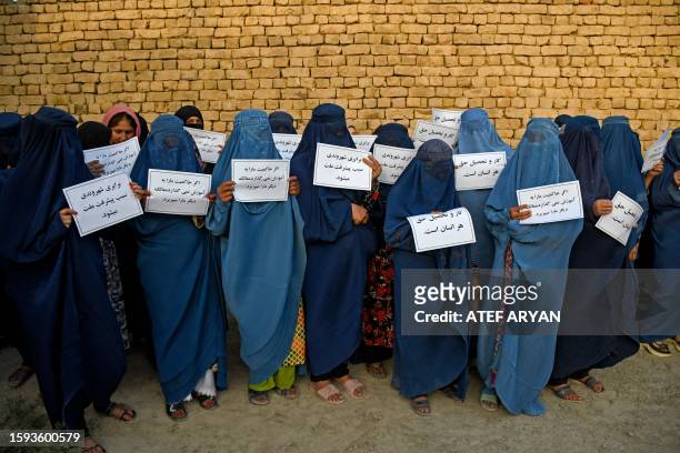 Afghan burqa-clad women hold placards as they protest for their right to education, in Mazar-i-Sharif on August 12, 2023.