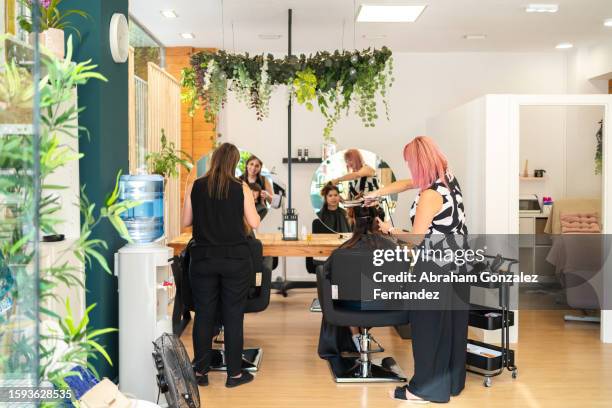 hairdressers making curls at a client's hair with curling irons - skönhetssalong bildbanksfoton och bilder