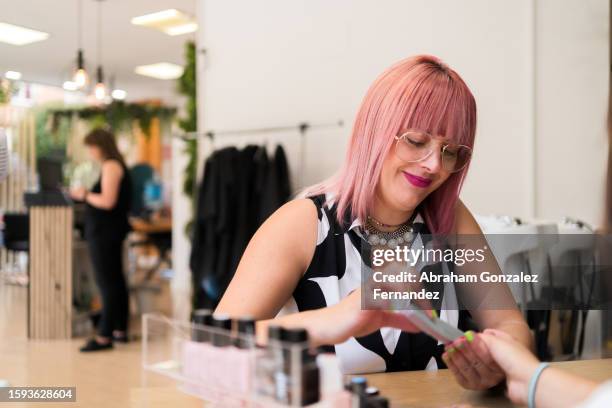 manicurist polishing the nails of a client - woman hairdresser stock pictures, royalty-free photos & images