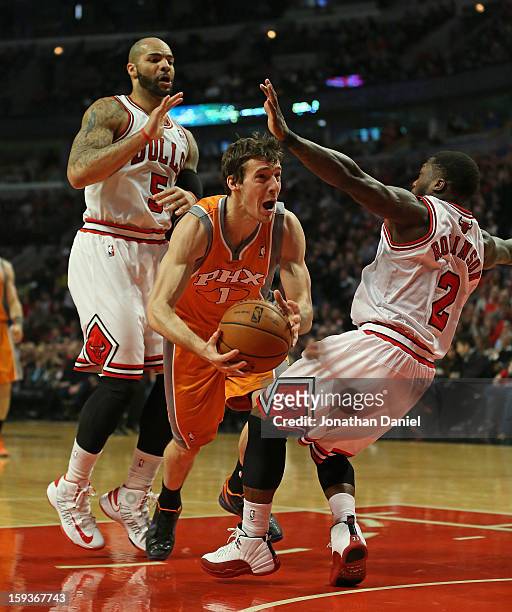 Goran Dragic of the Phoenix Suns falls as he tries to move between Carlos Boozer and Nate Robinson of the Chicago Bulls at the United Center on...