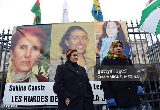 Two women of Kurdish origin take part in a demonstration on January 12, 2013 in Paris, standing in front of portraits of Sakine Cansiz, Fidan Dogan...