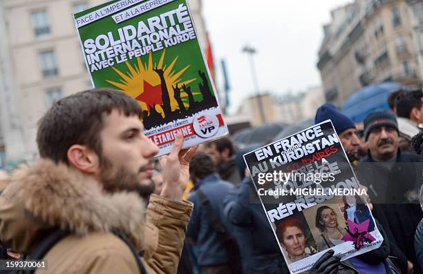 Man holds a placard reading "International solidarity with the Kurdish people" during a demonstration on January 12, 2013 in Paris, two days after...