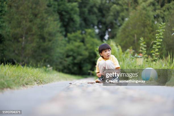 the asian little boy is walking slowly in the park - china football stock pictures, royalty-free photos & images