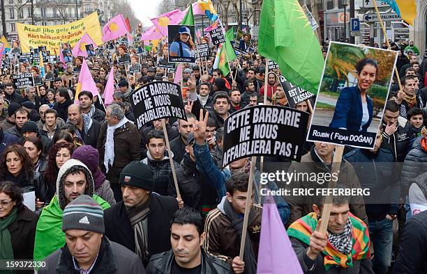 People hold placards reading : "This brutality will not weaken us" during a demonstration on January 12, 2013 in Paris, two days after Cansiz and two...