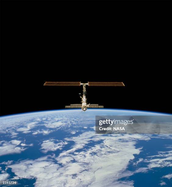 This picture of the distant International Space Station blended against the darkness of space and the blue Earth at its horizon is one of a series of...