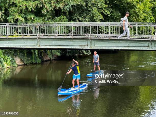 two men on a stand up paddle board (sup) on the river nahe in bad kreuznach, germany. - bad kreuznach stock pictures, royalty-free photos & images