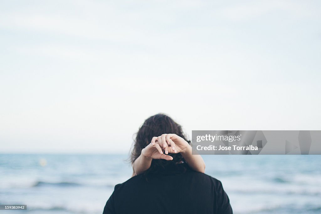 Backward man embracing a woman on the beach
