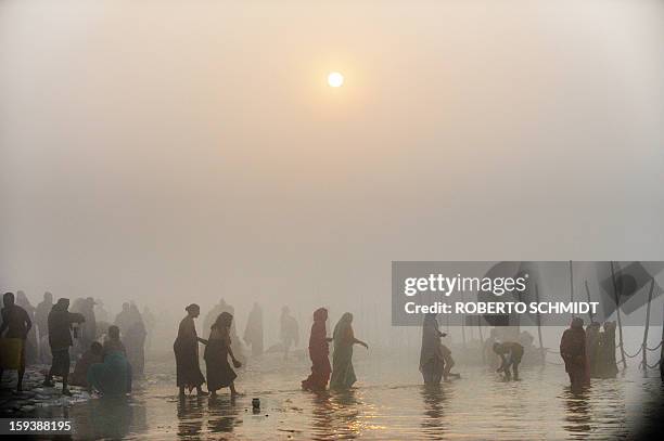 Devotees walk into the waters at the Sangham or confluence of the Yamuna and Ganges river during day break at the Kumbh Mela celebration in Allahabad...