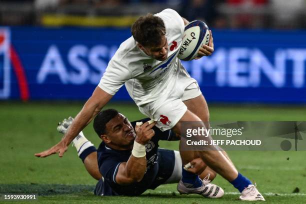 France's wing Damian Penaud is tackled by Scotland's inside centre Sione Tuipulotu during the pre-World Cup Rugby Union friendly match between France...