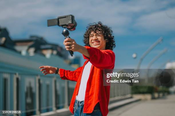 influencer asiático malayo generación z joven vlogging en la acera de la calle de la ciudad de kuala lumpur mirando a la cámara - vlogging fotografías e imágenes de stock