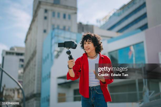 influencer asian malay generation z young man vlogging in kuala lumpur city street sidewalk looking at camera - asian generation z stock pictures, royalty-free photos & images