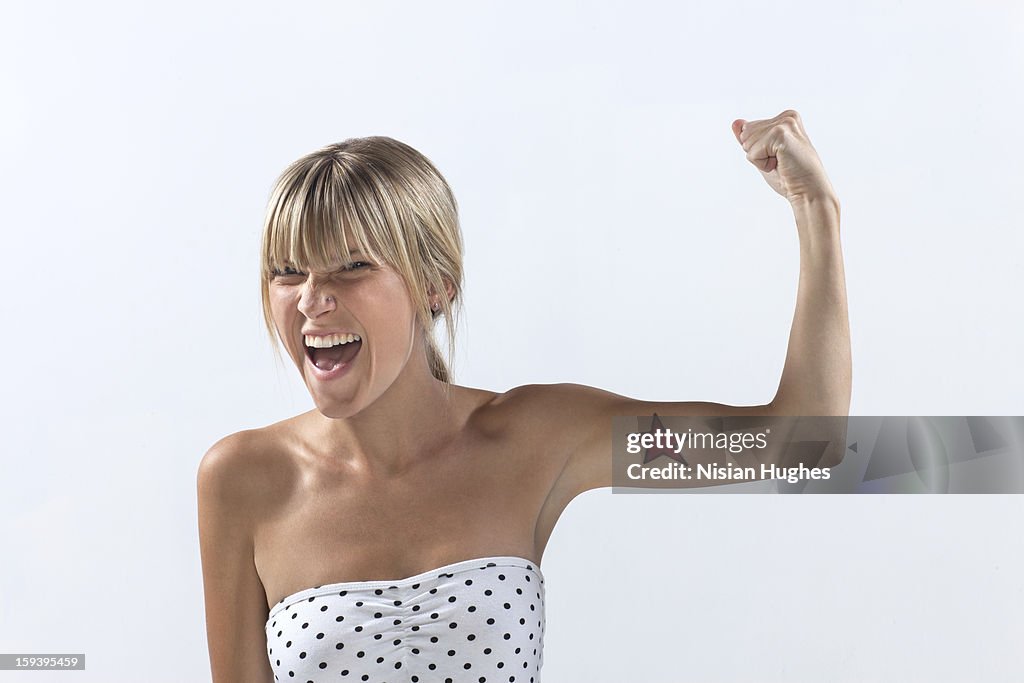 Portrait of young woman making a muscle