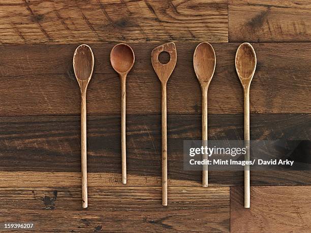 home cooking. a wooden table with a varied wood grain and colour. five wooden spoons in a row. - kochlöffel stock-fotos und bilder