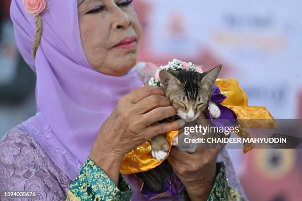 Dressed cat is held by its owner as they participate in the Cat Fashion Week held at a shopping mall in Banda Aceh, northern Indonesia, on August 12,...