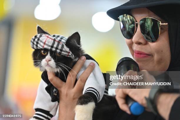 Dressed cat is held by its owner as they participate in the Cat Fashion Week held at a shopping mall in Banda Aceh, northern Indonesia, on August 12,...